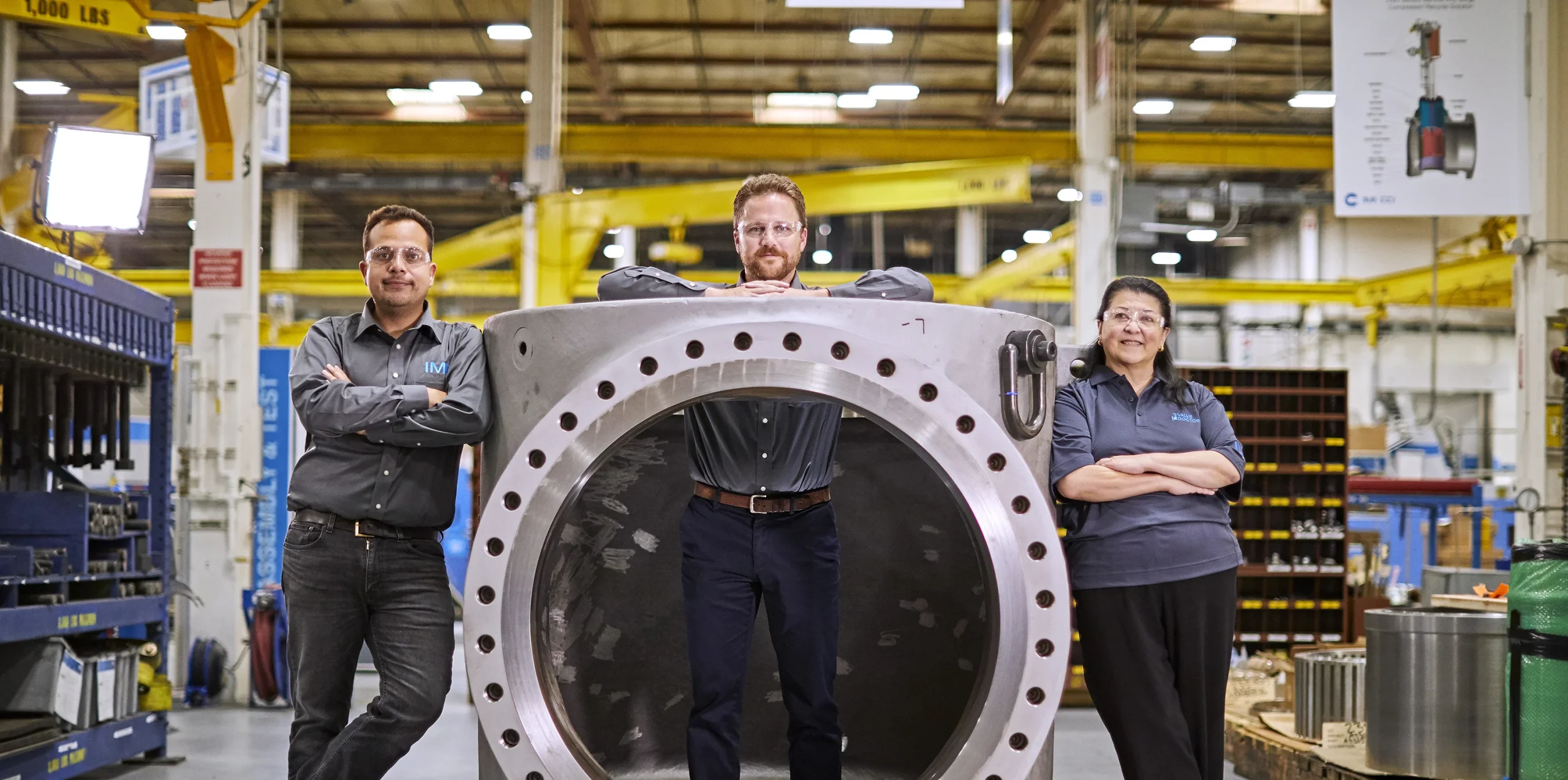 Three experts from IMI Critical Americas in RSM confidently display their mastery of control valve technology, striking a pose in and around a large control valve body, exemplifying IMI Critical's industry-leading expertise.