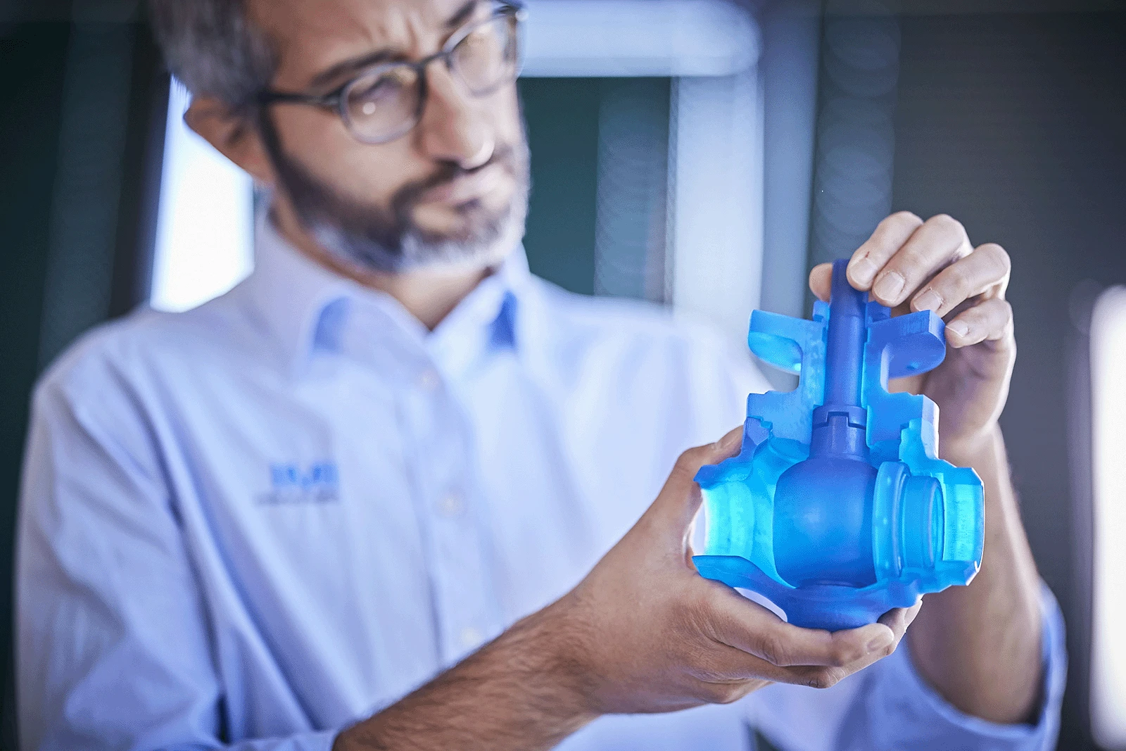 IMI Critical engineer displaying a 3D printed demo valve to colleagues in a well-equipped facility.
